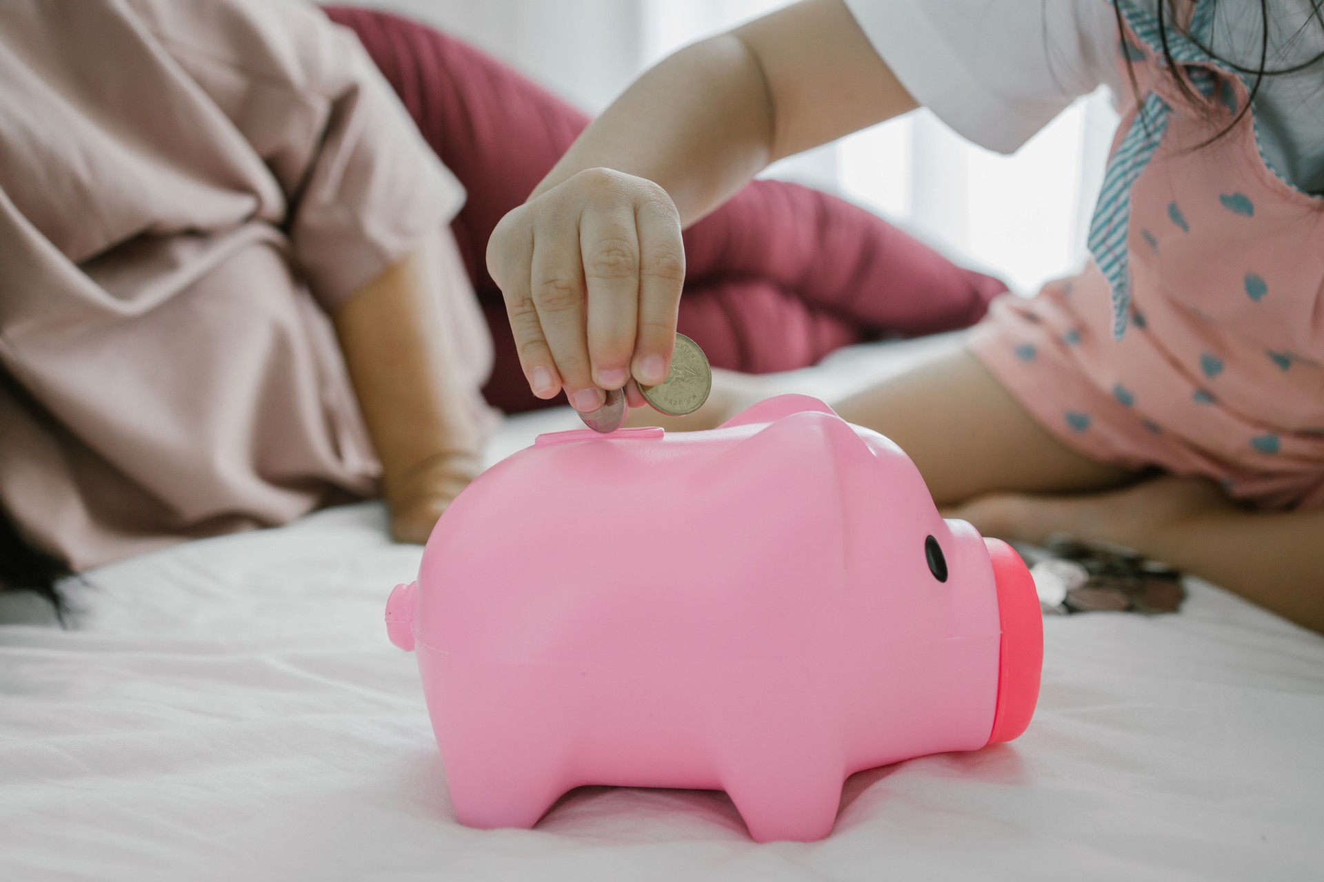 Cute Piggy Bank with Baby girl Puts Coins Inside beside mother