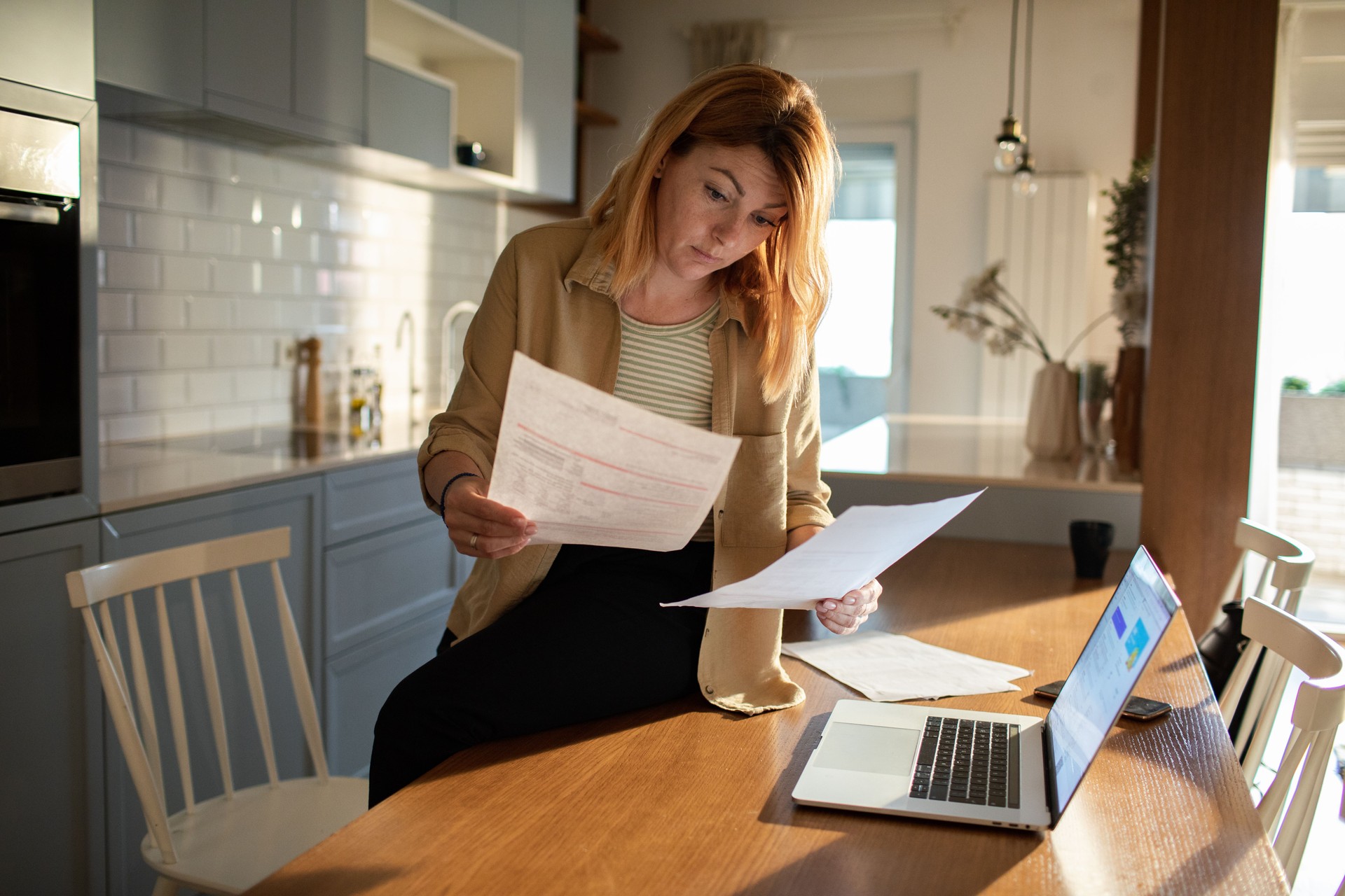 Young woman going over her finances at home while using her laptop